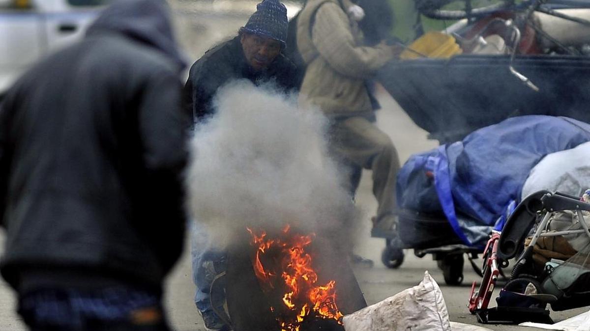 A fire provides some relief from the cold for homeless men near the Poverello House. Temperatures dropped to near freezing overnight Friday into Saturday morning in the Fresno area, according to the National Weather Service.