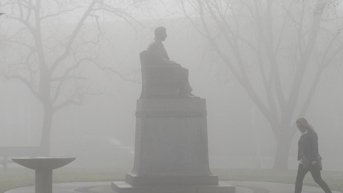 A woman walks by the Dr. Chester Rowell statue in Fresno’s Courthouse Park where thick morning fog enveloped the area on Tuesday, Jan. 31, 2017. Dr. Rowell was a Fresno physician who established the Fresno Republican newspaper in 1876. It eventually merged into The Fresno Bee.
