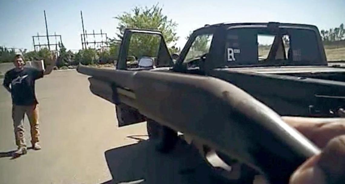 A screenshot image from a Fresno police body camera video showing one officer pointing a gun at Dylan Noble, who stands near his pickup with his left arm raised and his right hand behind his back.