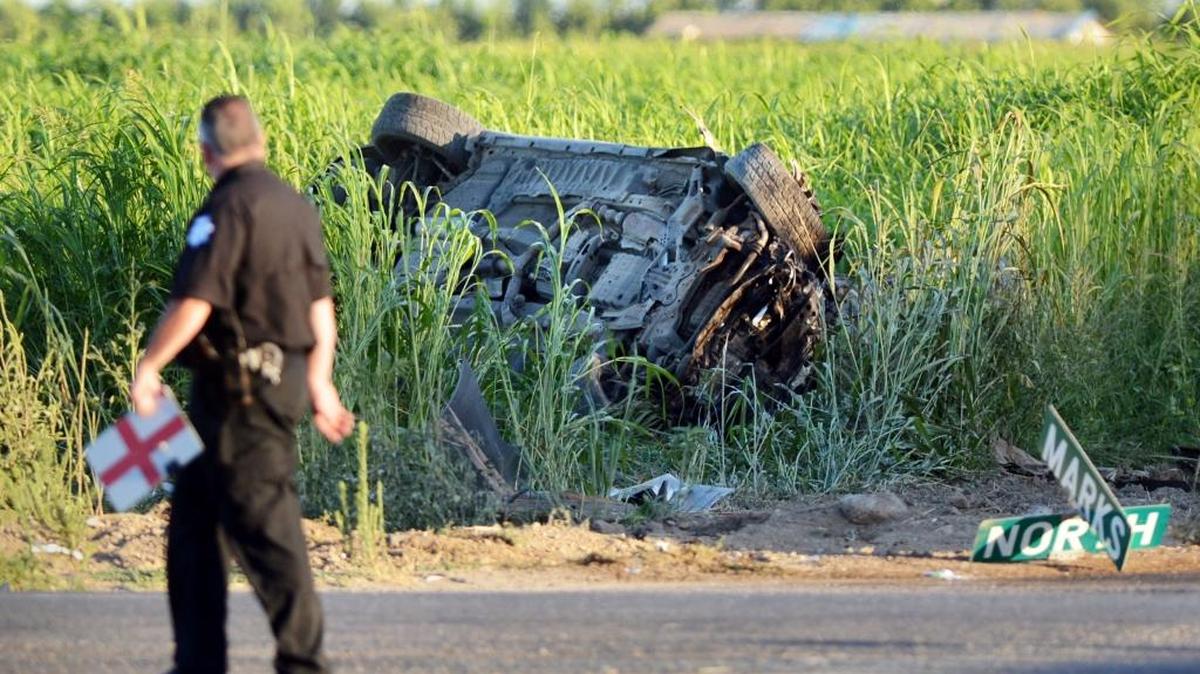 A Fresno police officer walks by an overturned car at Marks and North avenues after it was involved in a collision July 17, 2013. Ernest Grant, 55, of Fresno, was killed when his car was struck by a stolen Infiniti driven by Walter Levon McDaniel. The accident is now the subject of a civil trial.