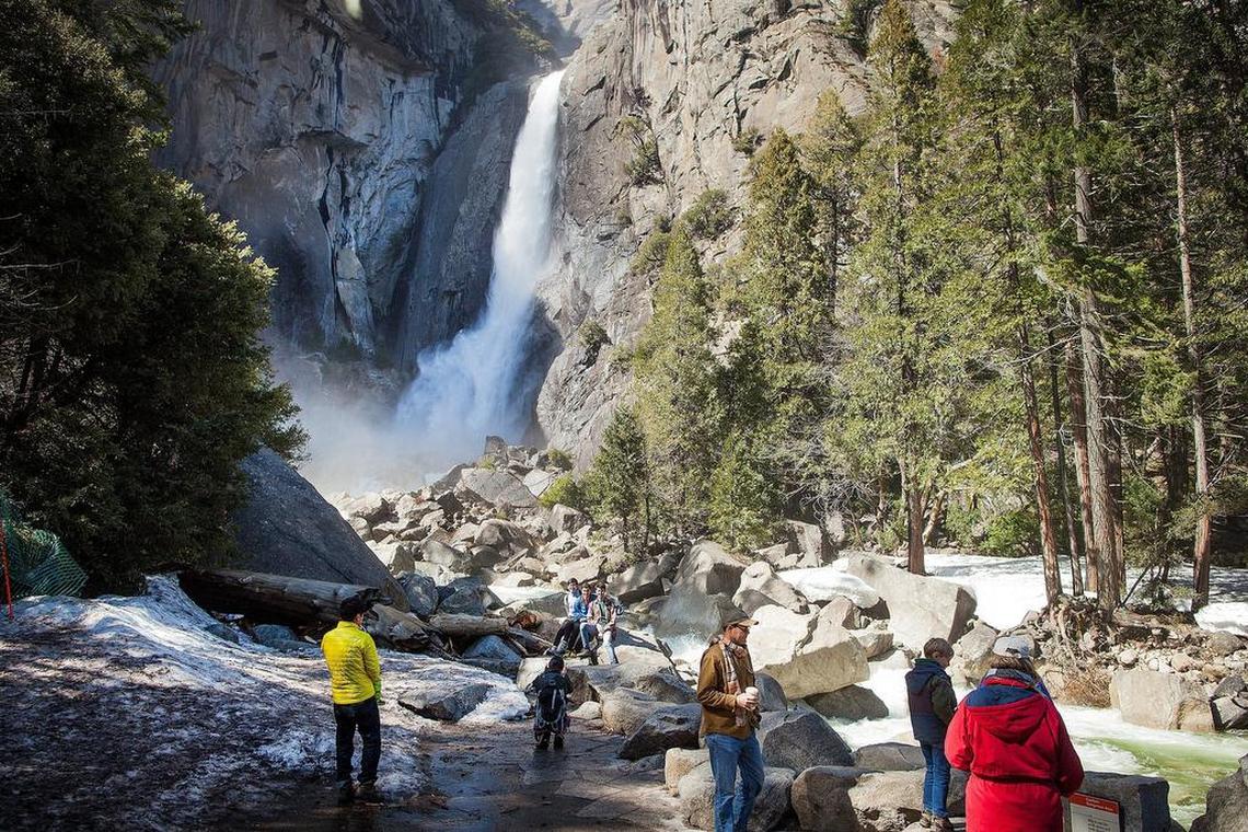 Tourists walk around the base of Lower Yosemite Fall as it thunders down the cliffs at Yosemite National Park on Thursday, March 23, 2017.