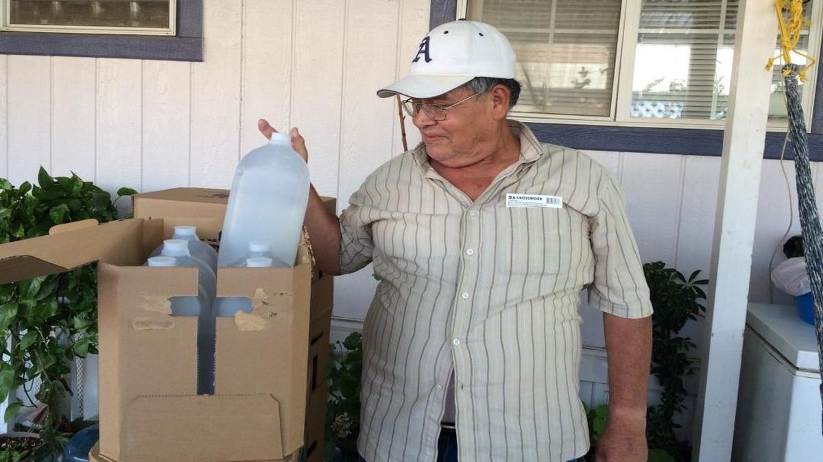 Ruben Luna of Cantua Creek examines bottled water when it was delivered in Cantua Creek and El Porvenir last year.