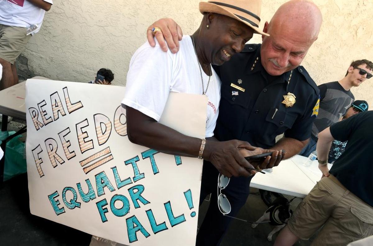 Charles Taylor shares something on his phone with Fresno Police Chief Jerry Dyer during the “Fresno’s Counter Rally Against Hate,” in the Tower District Saturday morning, Aug. 26, 2017.