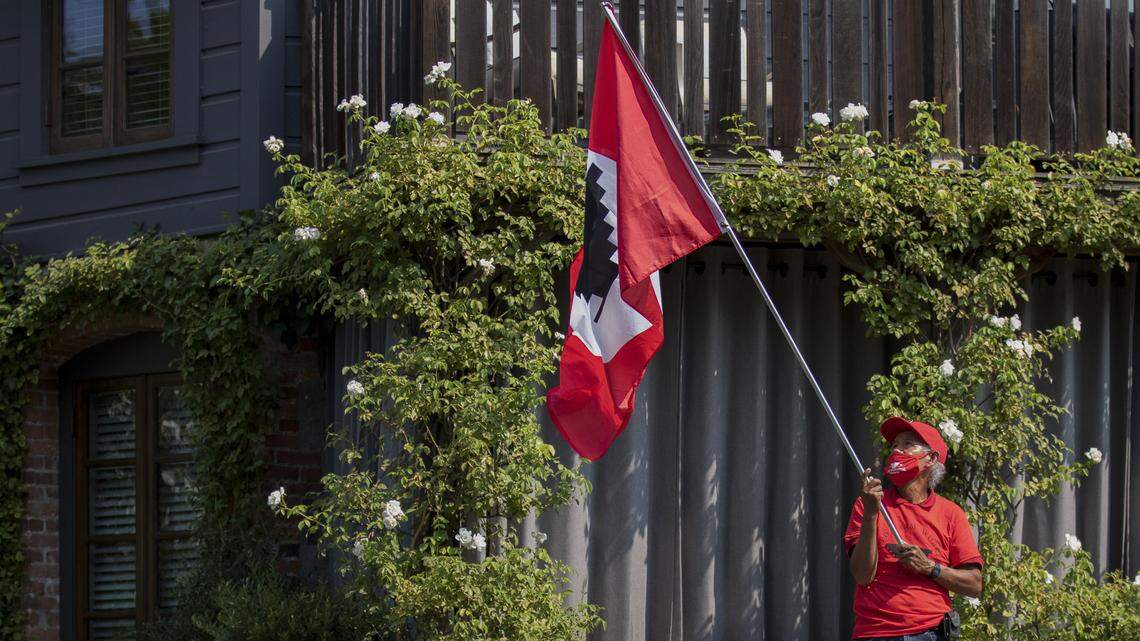 A demonstrator waves a UFW flag outside The French Laundry during a march from the renowned restaurant to Gov. Gavin Newsom’s winery, Plumpjack, in response to the governor’s veto of AB 616 on Sept. 25, 2021 in Yountville, CA. Photo by Rahul Lal for CalMatters