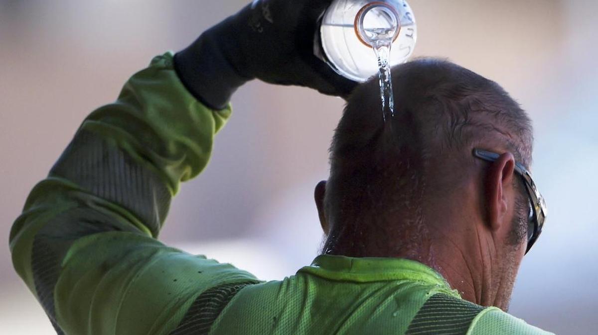 A construction worker pours a bottle of water over his head as he cools off in the shade at the end of the work day Wednesday, June 21, 2017 in Fresno.