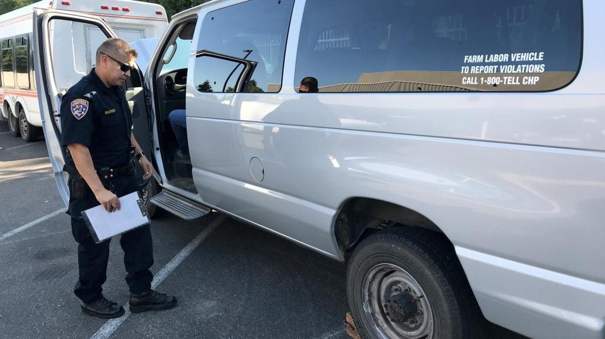 A SAFE officer inspects a farm labor vehicle at the Fresno area office.