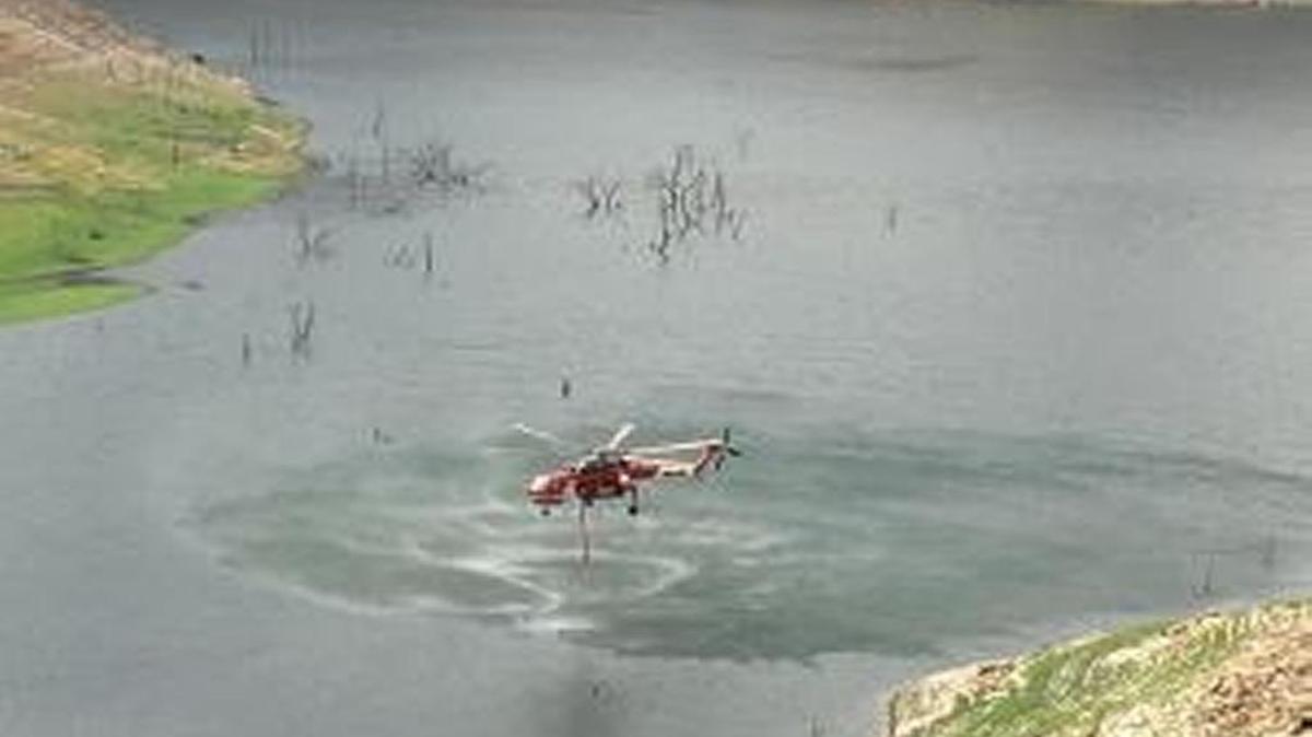 A helicopter fighting the Sacata Fire dips into Pine Flat Lake for a load of water to drop on the blaze.