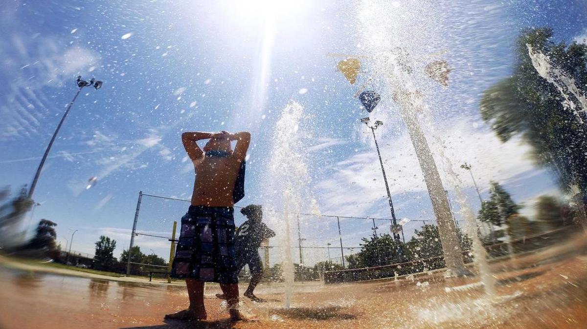 Malachi Uribe, 4, stands soaking and keeping cool with his shirt tied around his neck as a cape in the water feature at Dickey Playground on a hot Monday afternoon, in Fresno.