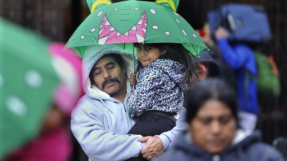 Federico Ramirez carries his daughter, Sarah Ramirez, along Fulton Mall, as they do last-minute shopping on Christmas Eve, during the rain storm.