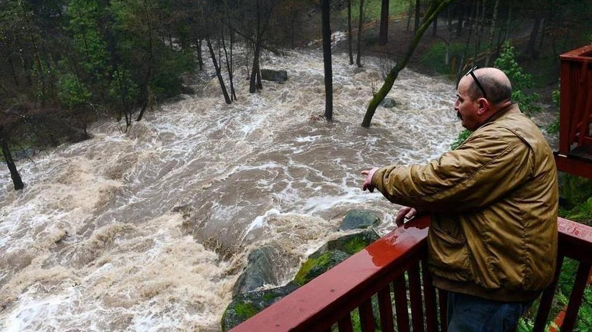 Nick Gonsalves of Oakhurst watches Lewis Fork Creek overflow near homes at Yosemite Forks Estates, where he works doing maintenance and construction, Tuesday, Feb. 7, 2017.