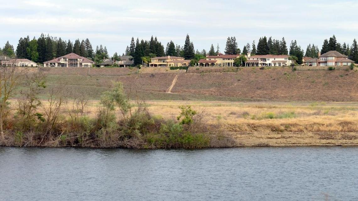 Large homes are seen on the bluffs above a pond near the San Joaquin River in north Fresno in May. The area is in crosshairs of homeowners and members of the public trying to agree on access to the river area.