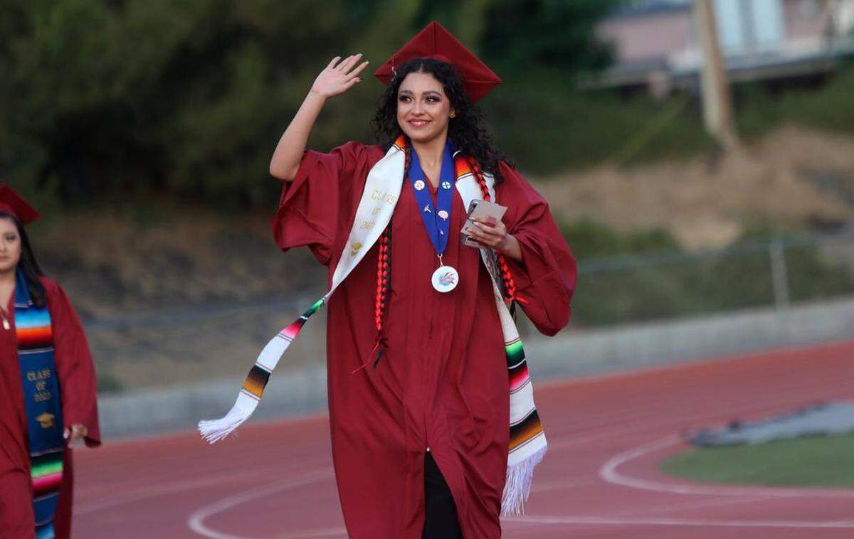 A graduate walks in at the start of the first graduation ceremony for Matilda Torres High School at Madera Memorial Stadium on June 10, 2023.