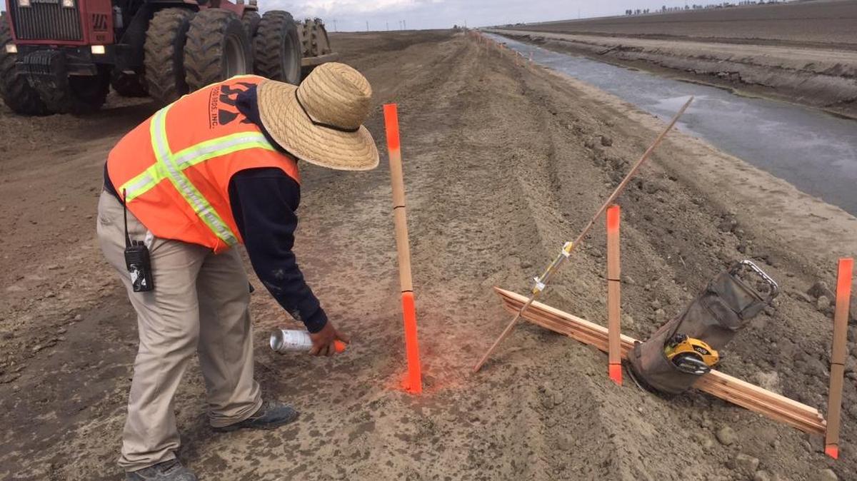 Antonio Rojas prepares stakes showing how high the dirt should be to raise a levee near Corcoran.