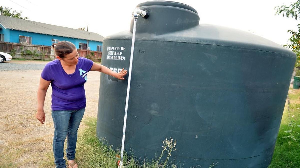 
Aida Beltran, 41, checks the water level of the county tank of water in her front yard in East Porterville. The family is now enduring the drought after their well went dry last November. The Beltrans own their home. Tulare County supervisors this week approved a plan to take free water to renters who need it.
