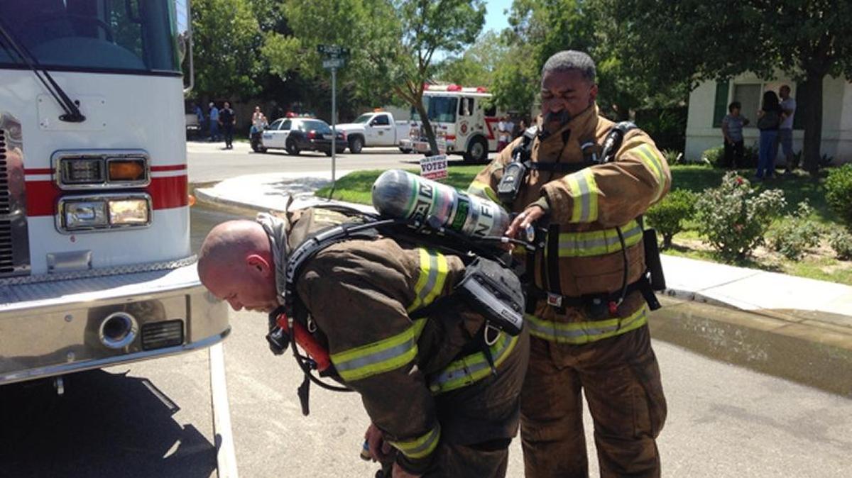 A pair of Fresno Fire Department firefighters take off their breathing gear after battling a house fire in Kerman in this 2013 file photo. The city of Fresno provides fire services in Kerman and the rest of the North Central Fire Protection District west of Fresno under a 30-year contract approved in 2006.