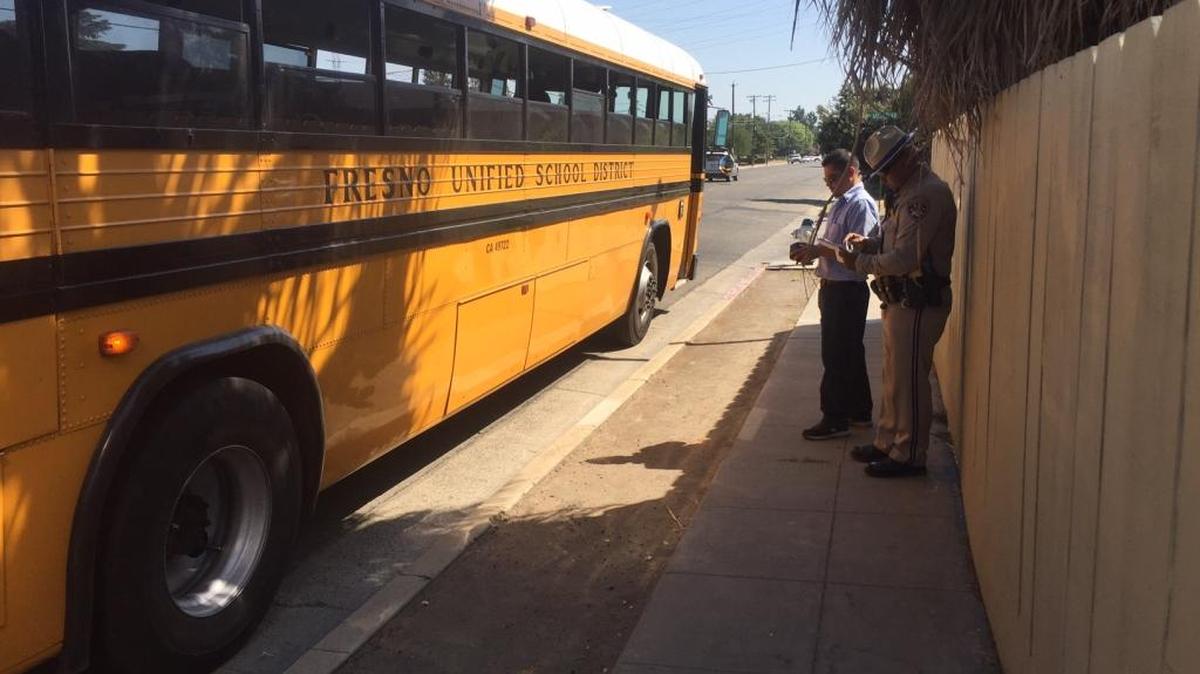 A California Highway Patrol officer, right, investigates a Fresno Unified school bus involved in a collision with a boy on a bike.
