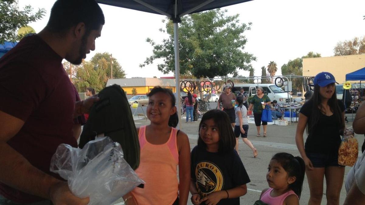 Andrew Chavez hands out backpacks to children at a Huron farmer’s market. Chavez and his business partner Luis Valencia are hoping to bring the medical marijuana industry to town.