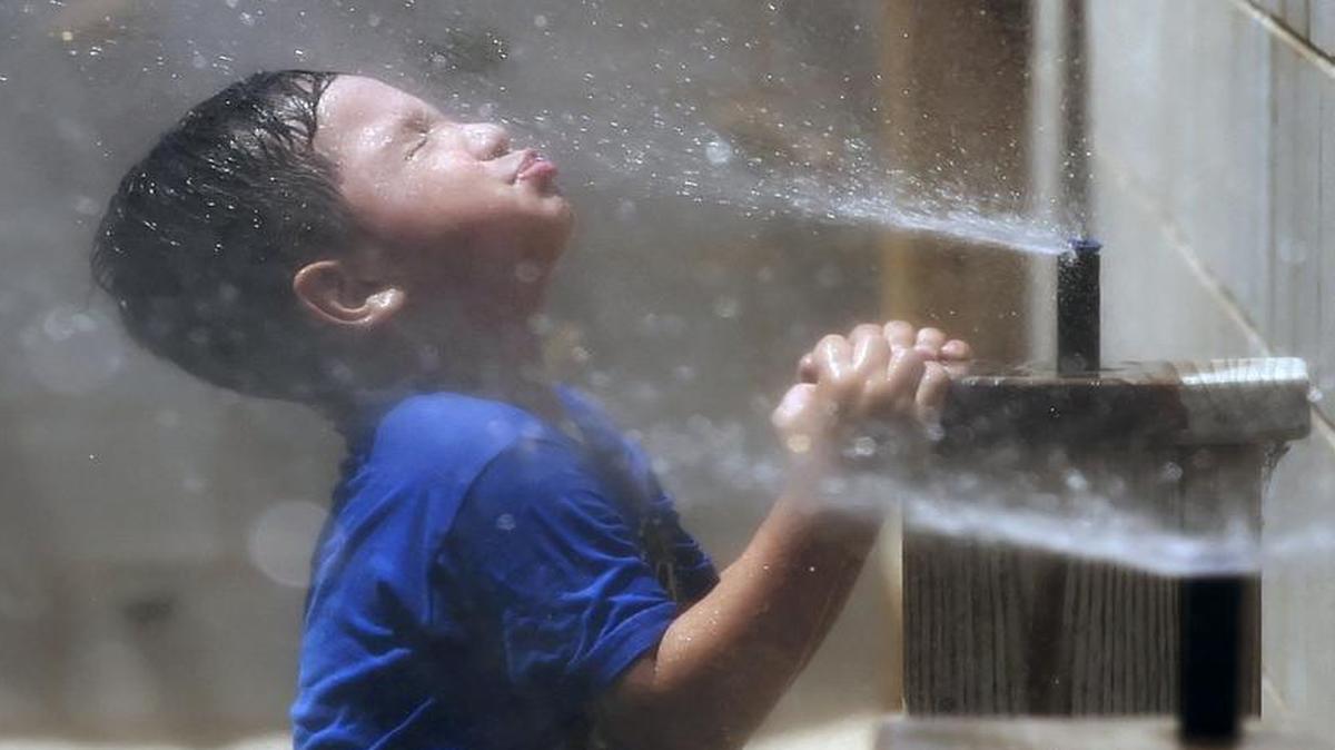 Dominick Perez, 4, pulls himself up to get cool in the misters while playing in the playground at Lighthouse for Children Child Development Center, Wednesday, June 1, 2016 in downtown Fresno, Calif.