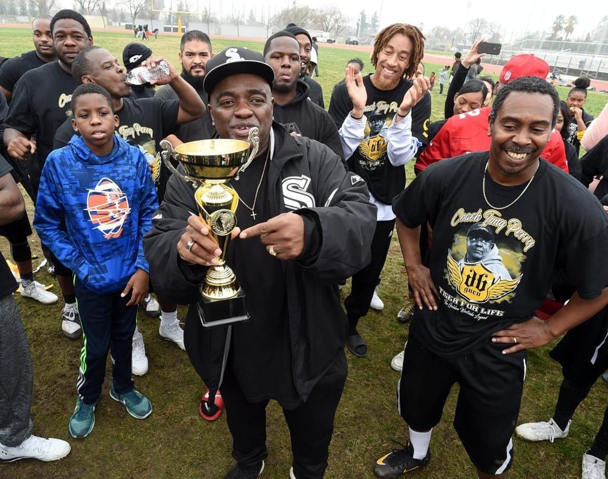 Brian King, director of the Fresno EOC Street Saints, center, with pastor Joby Jones, right, shows off the trophy his team won after the inaugural Community Flag Football Game against members of the Fresno Police Department ’s Southwest Fresno Policing District on Wednesday, Jan. 3, 2018. The Stop the Violence and Fresno EOC Street Saints team won 27-0.