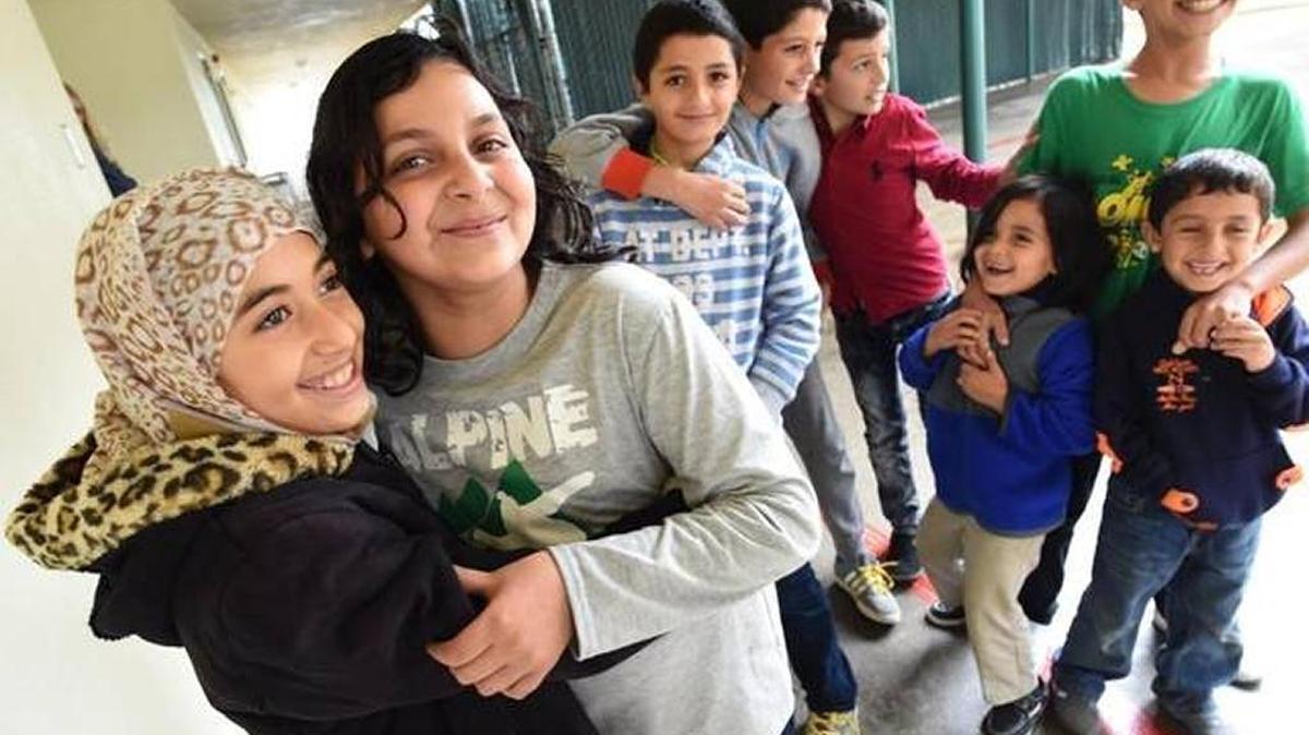 Bassmah Abukouydeer, left, and Nifeen Al Awad, hug alongside fellow Syrian refugees at their new Fresno school in 2016.