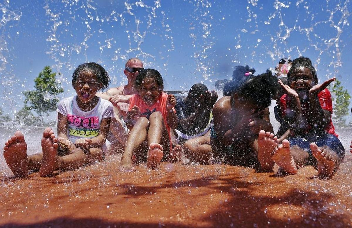 Children, and one adult, are drenched as a large bucket of water showers on them at Fresno’s Inspiration Park Sunday afternoon.
