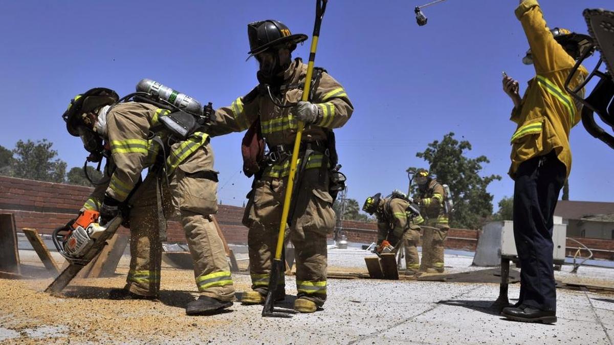 Fire crews cut into a roof while being recorded by video, to the right, as Fresno, Clovis and Fresno County fire departments conduct a training exercise on a rooftop Monday, June 2, 2014 in Fresno, Calif.