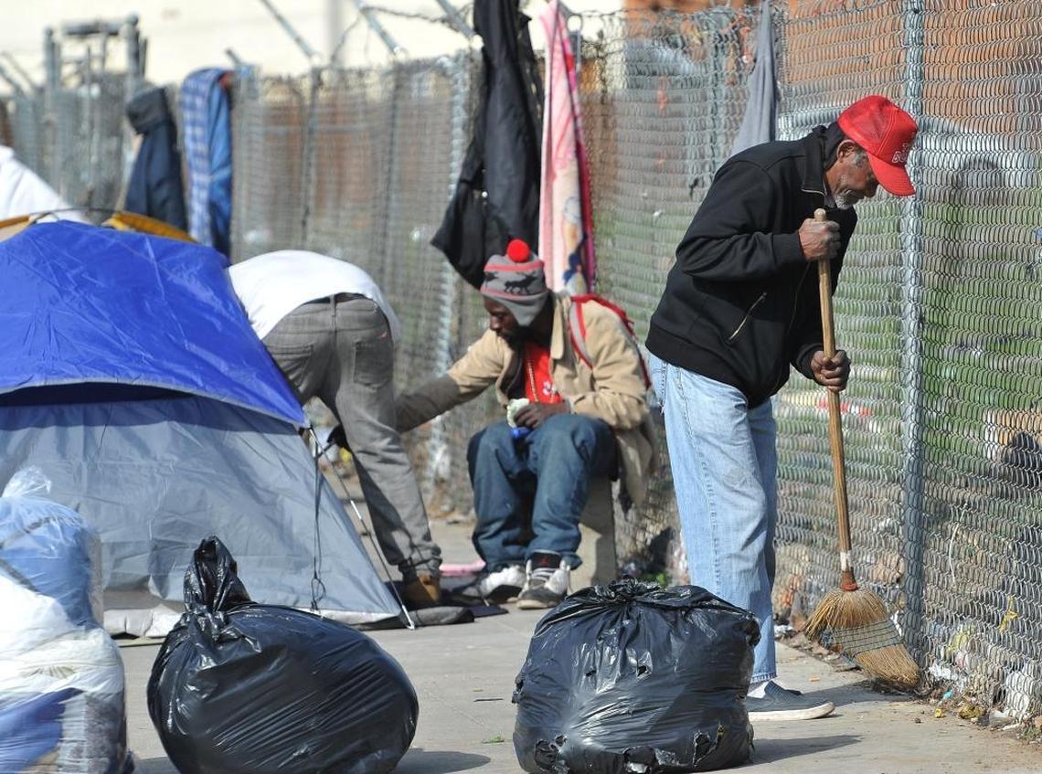 Jimmy Gregory, 63, tidies up around his tent where he and other homeless people live on F Street.