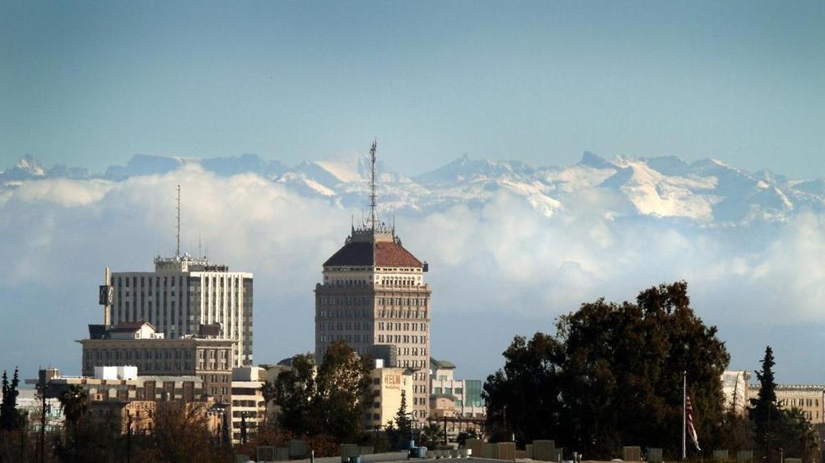 Fresno Bee file image of the downtown Fresno skyline seen below snowcapped Sierra Nevada mountains and clouds along the foothills in December 2009.