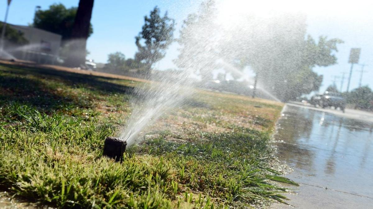 Sprinklers run on a grassy area in front of Eaton School in Fresno in this 2014 photo. Fresno plans to ease its summer watering restrictions for this summer following a winter of plentiful rain.