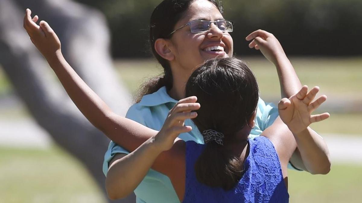 Eliza Basaula, 7, reaches up to hug her mother Kamala Basaula as they play on the Fresno State Amphitheater lawn on a cool Sunday afternoon. More unseasonably cool days are ahead.