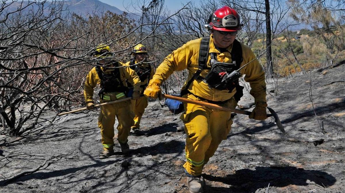 Tulare Fire captain Johnny Garcia, right, leads firefighter Frank Nunez, left, and engineer Eric Ferreira, center background, through a charred hillside putting out spot fires on private property just west of Road 426 near Manzanita Drive where the Courtney Fire burned through homes and forest near Bass Lake. Photographed Tuesday, Sept. 16, 2014 near Oakhurst. Madera County is considering a new tax to help fund more firefighters.