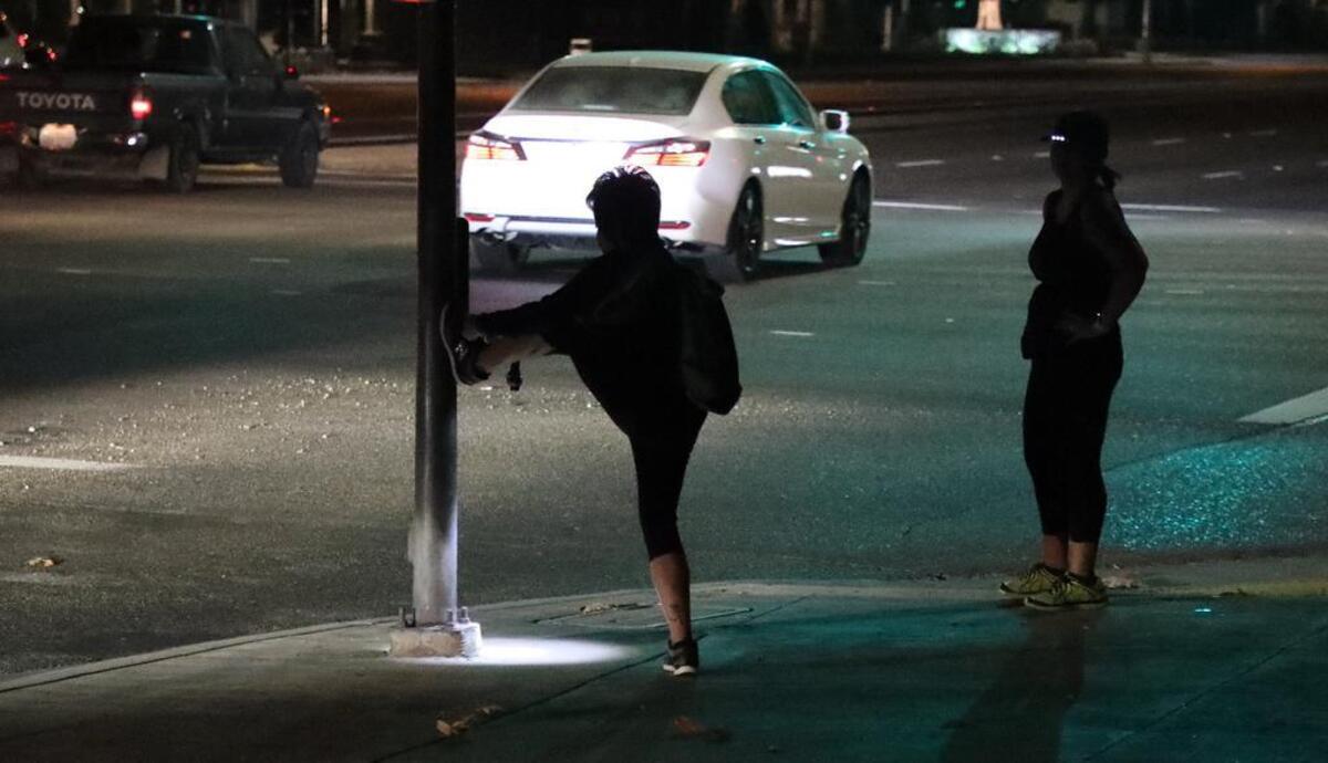 A woman stretches her leg at the corner of Friant Road and Auduban during a pre-dawn run in tribute to Fort Washington Elementary School administrator Gavin Gladding, who was killed a week ago today by a hit-and-run driver while training for a marathon.