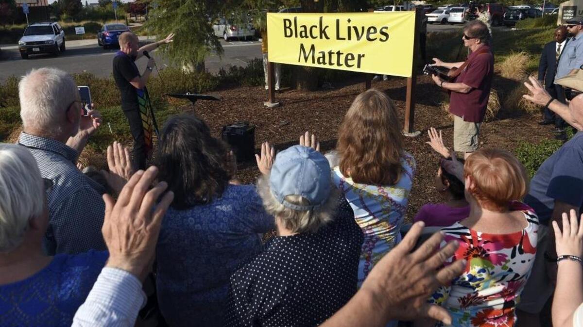 Members of Unitarian Universalist Church of Fresno raise their hands during the blessing as twin Black Lives Matter banners were unveiled outside the church on Alluvial Avenue Aug. 16, 2017 in Fresno.