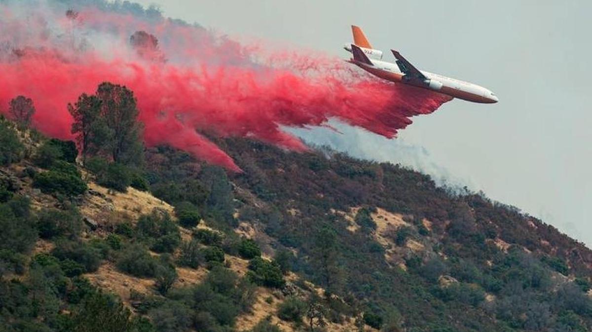 An air tanker drops fire retardant on a hilltop next to Lake McClure to battle the Detwiler Fire near Coulterville.