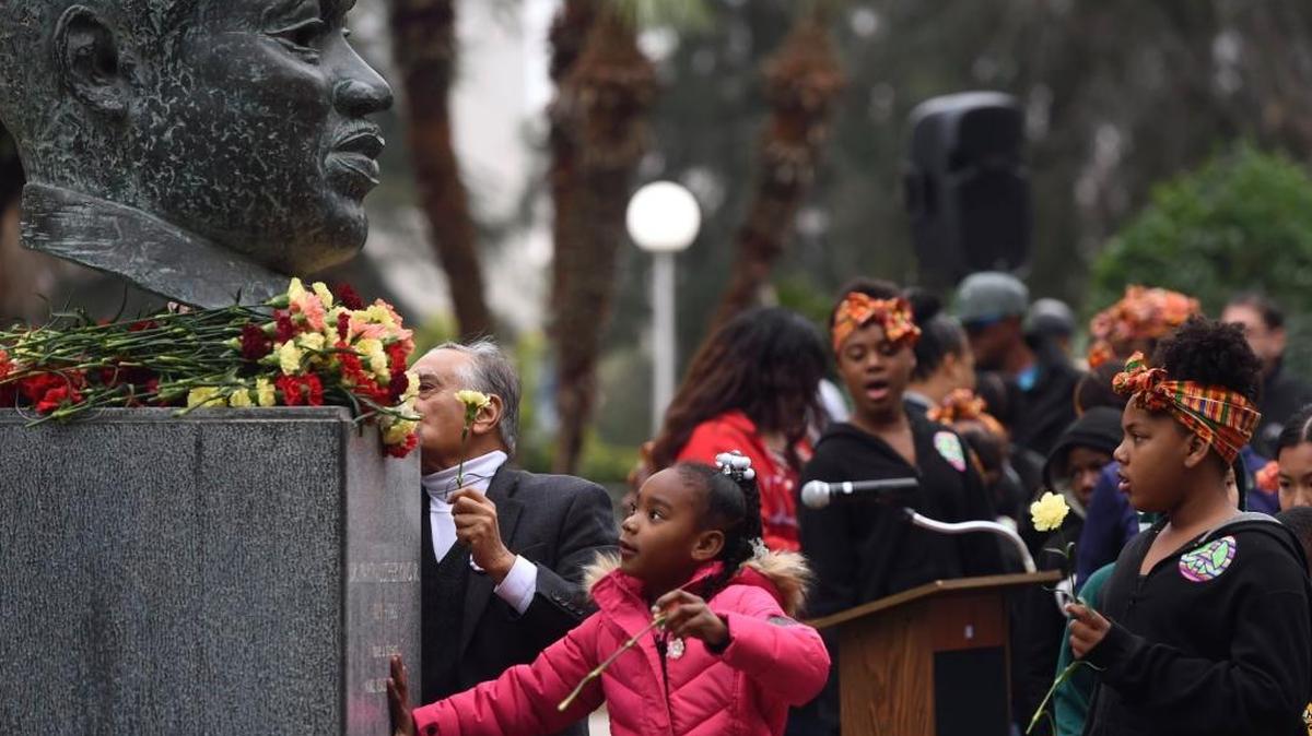 Children from King African American Dance Troupe lay down carnations at the bust of the Rev. Martin Luther King Jr. in Courthouse Park on Jan. 12.