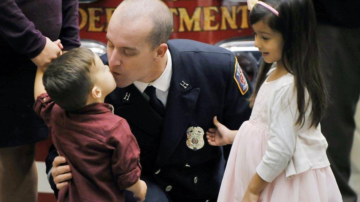 John Pepper Jr., center, leans in to kiss son Kellen Pepper, 2, left, as his daughter Olivia Pepper, 5, right, watches after Olivia pinned a new shield to her dad who was promoted from firefighter to captain during the Fresno Fire Department’s Awards And Promotional Ceremony held Tuesday morning, November 3, 2015 at Fresno City Hall in Fresno, Calif. Twelve awards were given and 16 promotions recognized in a ceremony attended by family and supporters.