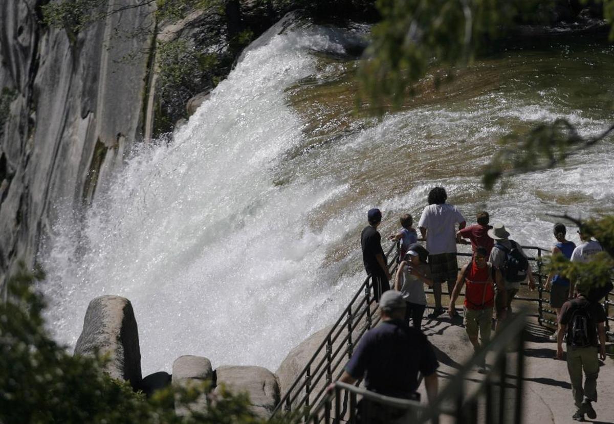 Hikers reach the vista point at Vernal Fall after hiking the Mist Trail next to the Merced River above Vernal Fall in Yosemite National Park.
