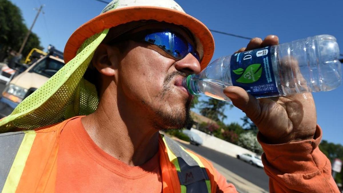 Miguel Lunar of Madco Electric takes a swig of water during work at Fresno’s McKinley and Shields avenues to install traffic sensors under the roadway surface in June 2016.