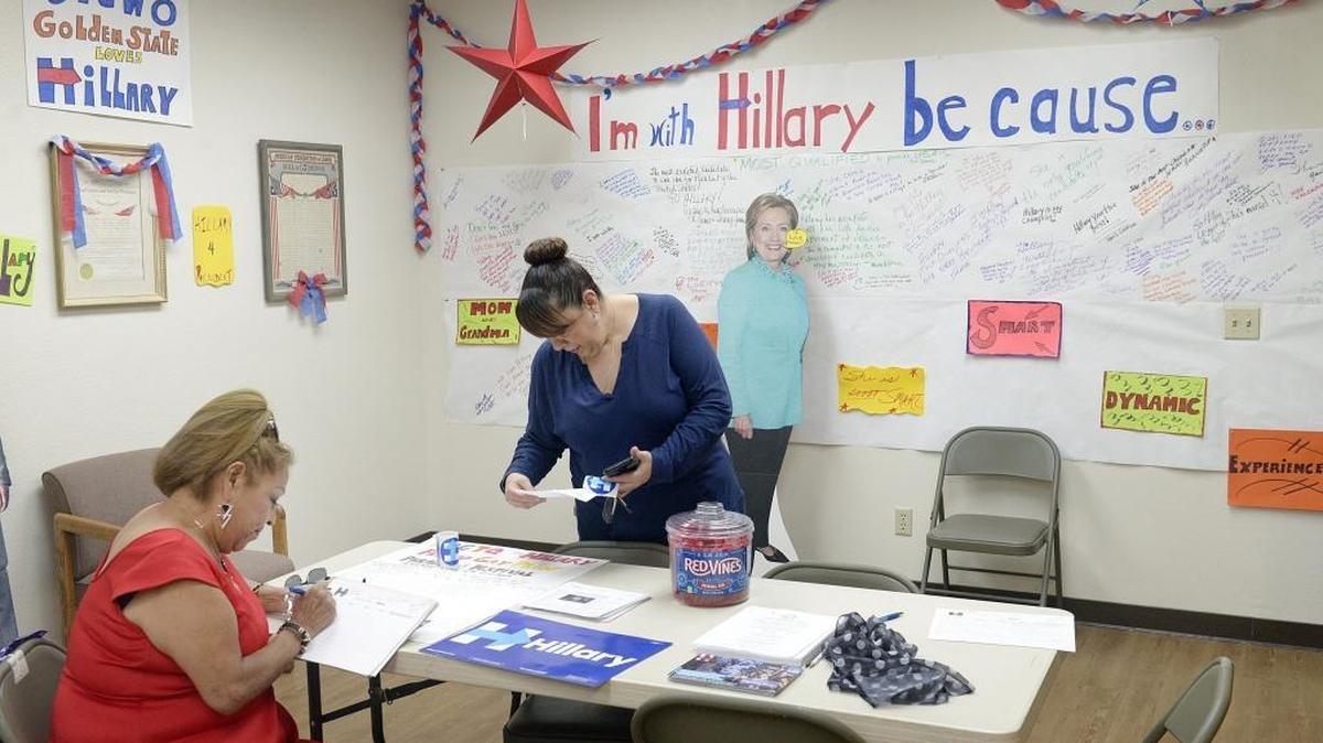 Lucha Prado, center, of Fresno reads campaign material as Olivia Hastings of Fresno fills out volunteer information at the Hillary Clinton for President campaign office in Fresno, Wednesday, June 1, 2016.