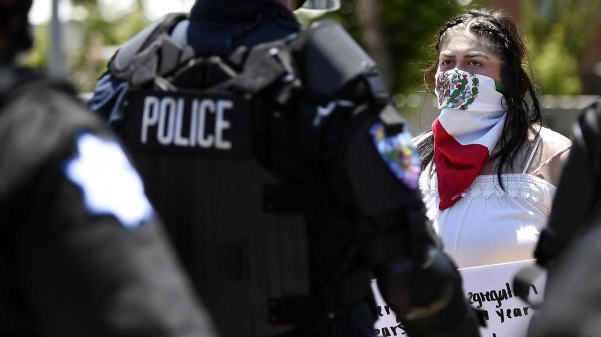 A young woman stands against a wall of late enforcement before being arrested as the line advanced along venire Avenue following the rally for GOP presidential nominee Donald Trump held Friday, May 27, 2016 in downtown Fresno, Calif.