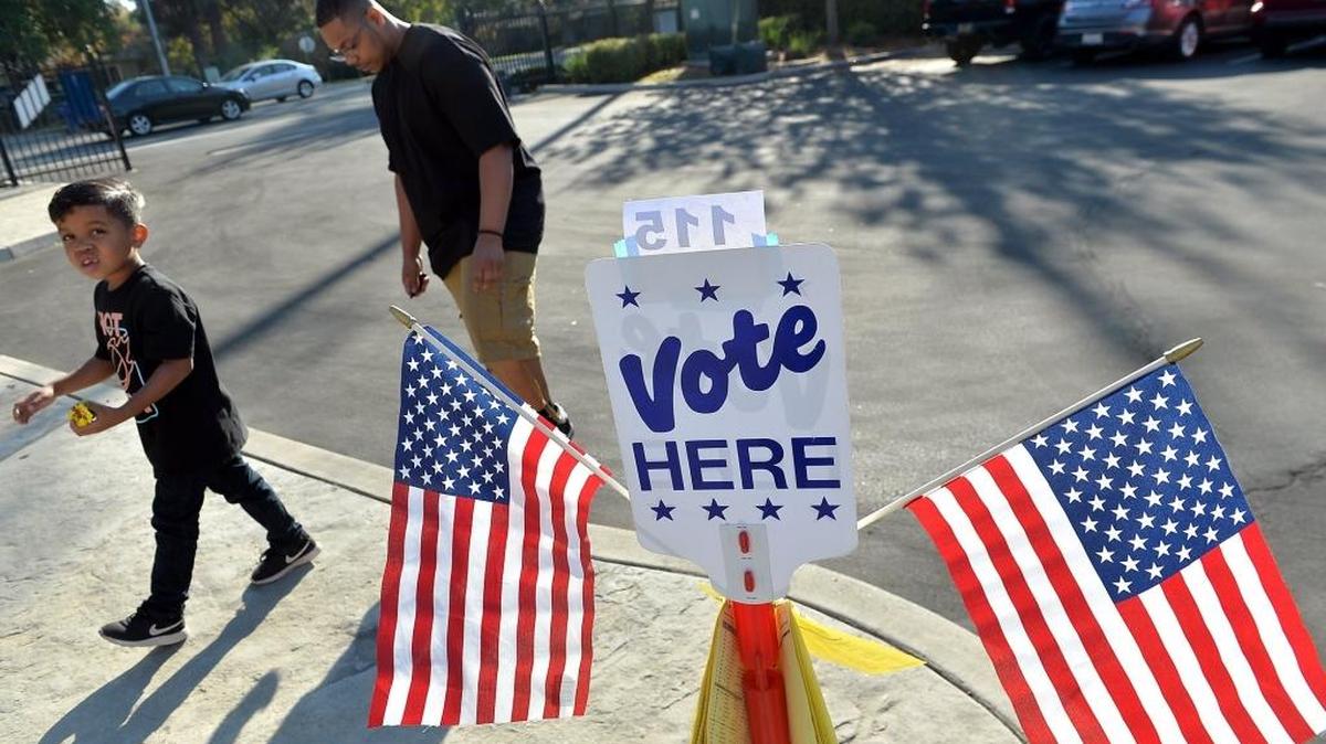 Antwone Atterberry Burrell, 6, left, and his father, Delbon Atterberry Burrell, both of Fresno, walk past election signs on Tuesday, Nov. 8, 2016, at the Boy Scouts of America polling place in northwest Fresno.