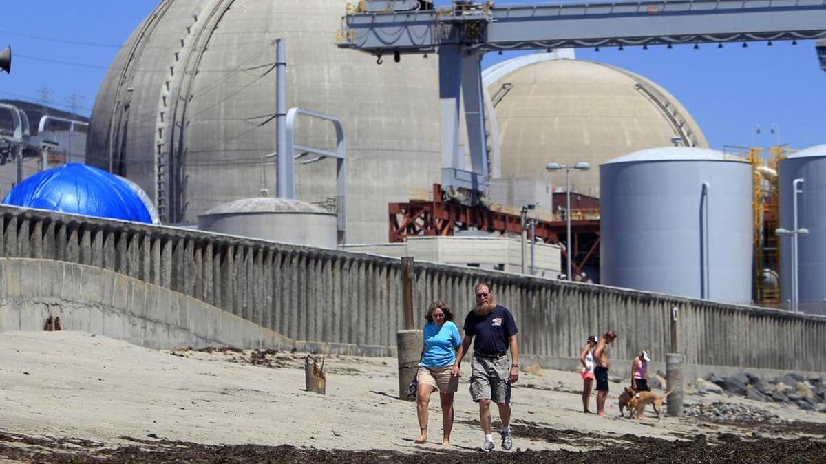 Beachgoers walk near the San Onofre nuclear power plant in San Clemente. The plant was shut down in 2012. That closure led to a secret deal to have utility ratepayers bear most of the cost, then a scandal when the deal was disclosed. Now the Public Utilities Commission is reopening the case.