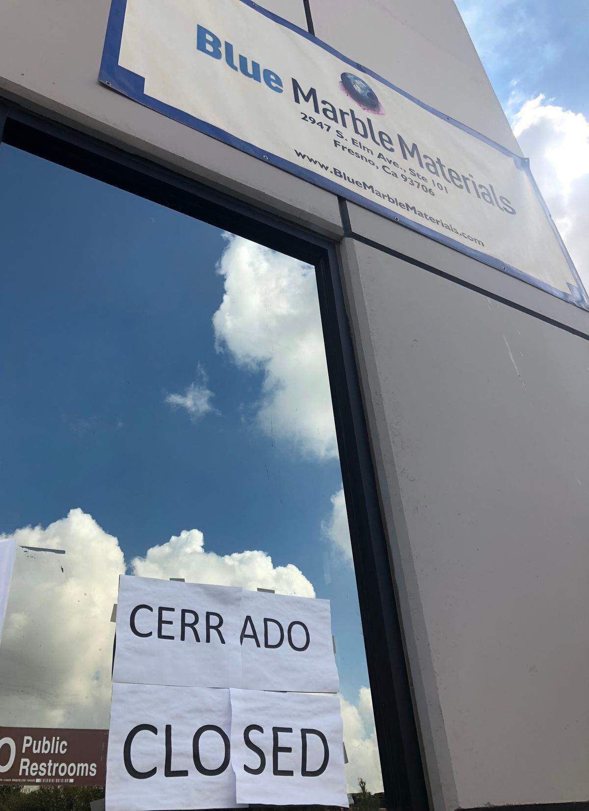 Signs taped to a front window proclaim in Spanish and English the closure of Blue Marble Materials’ mattress-recycling center on Elm Avenue in south Fresno on Thursday, Oct. 4.