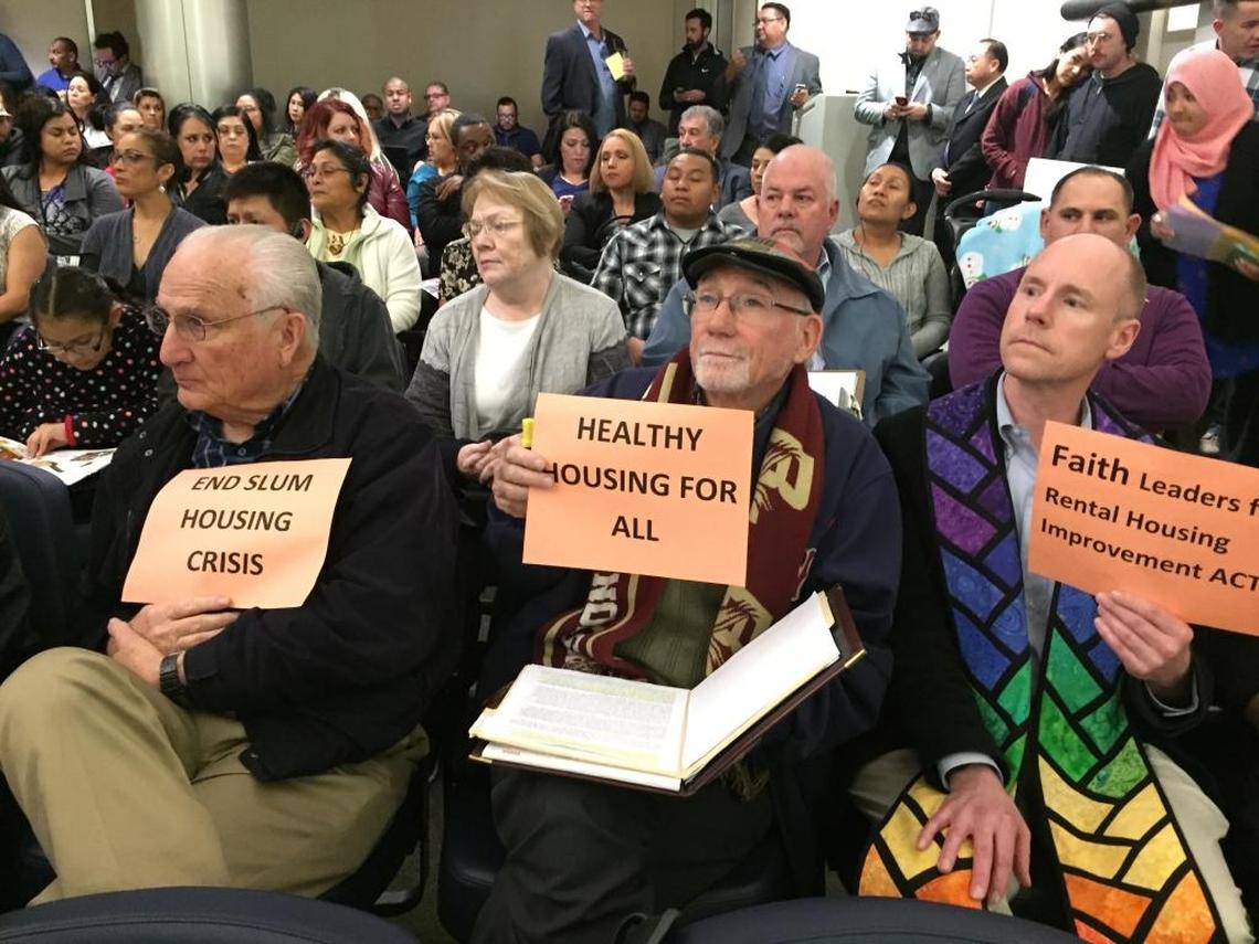 From left, St. Paul Catholic Newman Center deacon William Lucido, Roman Catholic Diocese of Fresno director of social ministry Jim Grant and Unitarian Universalist Church of Fresno Rev. Tim Kutzmark hold signs during a City Council meeting at which Fresno Mayor Lee Brand presented his rental housing inspection plan on Thursday, Feb. 2, 2017, at City Hall in Fresno.