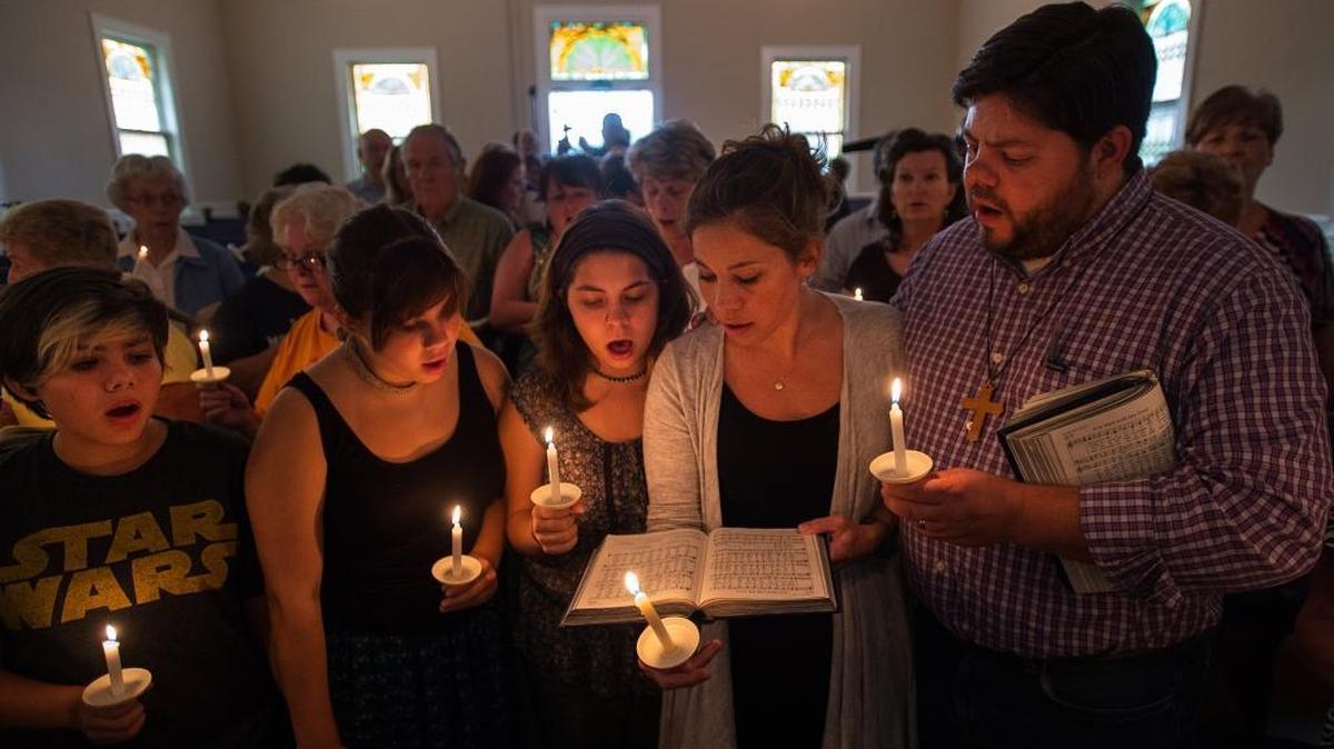
Community supporters sing a hymn during a vigil for television journalists Alison Parker and Adam Ward, who were killed in a shooting Wednesday during a live on-air interview in Moneta, Va.

