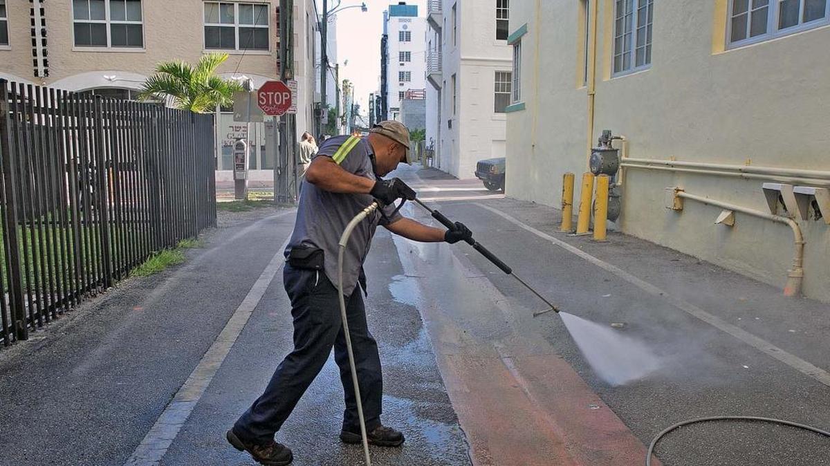 A Miami Beach sanitation worker washes down an alleyway Aug. 19, 2016, with high pressure hot water to kill mosquito larvae. Federal health officials warned pregnant women to avoid South Beach because of the Zika virus.