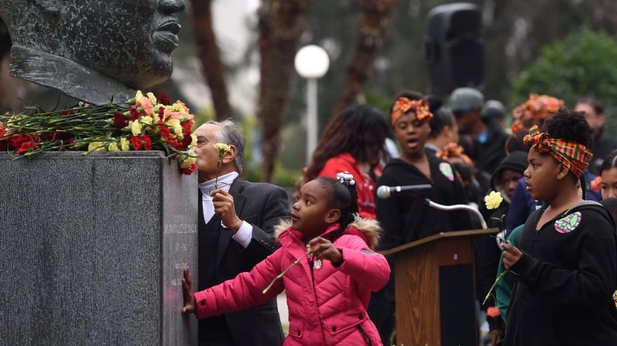 Kids from King African American Dance Troupe are some of the last to lay down carnations at the bust of Martin Luther King, Jr. as about 200 people attended the annual garlanding ceremony in Courthouse Park Friday in downtown Fresno.