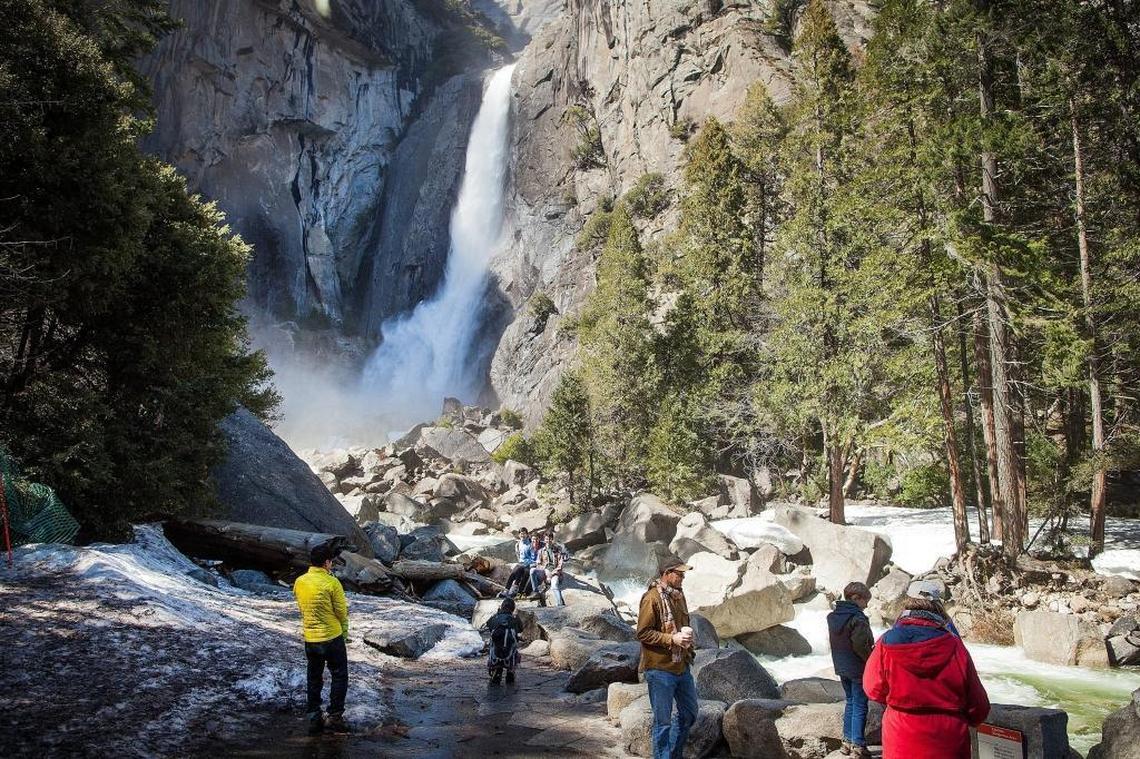 Tourists walk around the base of Lower Yosemite Falls as it thunders down the cliffs at Yosemite National Park on March 23, 2017.