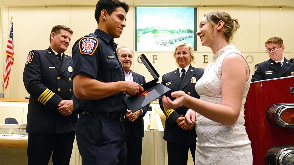 Fresno firefighter Rene Gonzales receives the Medal of Bravery from Brooklynn Banta of Madera at Fresno City Hall on Wednesday, April 26, 2017.