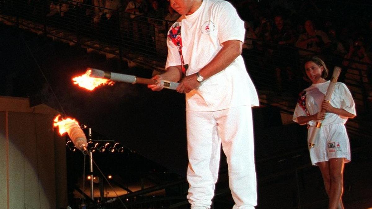 Swimmer Janet Evans looks on as Muhammad Ali lights the Olympic flame during the 1996 Summer Olympic Games opening ceremony in Atlanta, in this July 19, 1996, photo.